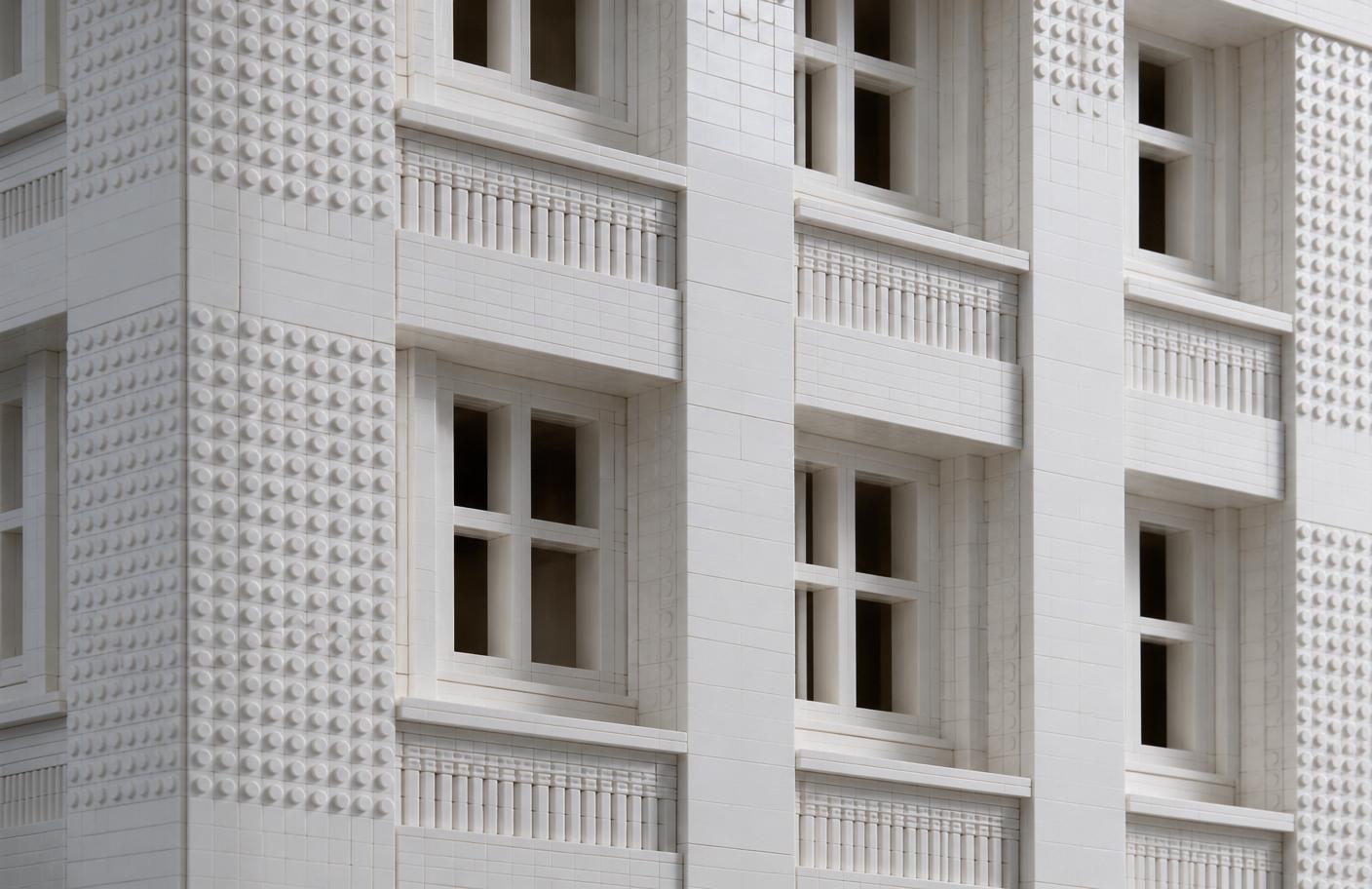 Close-up of a white monochrome brick facade showing recessed windows, horizontal banding, and mixed smooth and studded textures