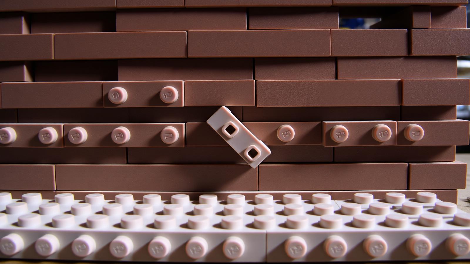 Macro shot of overlapping brown bricks on a wide baseplate with a cross-support plate